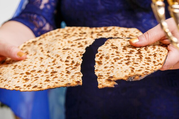 Photo a jewish woman at the passover seder table breaks the shmura matzah horizontal photo