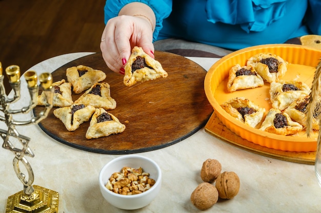 A Jewish woman stacks gomentashi cookies for the Purim holiday on a wooden board