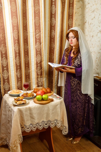 A Jewish woman in a veil falling from her hair prays at the festive table on Rosh Hashanah