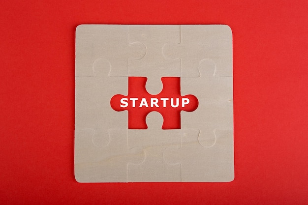 Pezzi di un puzzle con la parola startup su sfondo rosso