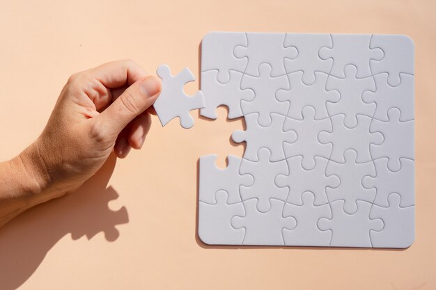 Jigsaw puzzles unsorted pieces on pink background with someones hand holding one peace