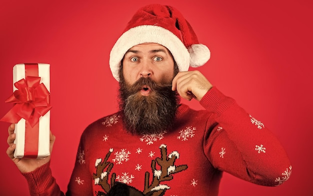 Jingle bells wintervakantie feest volwassen man viert nieuwjaar bebaarde hipster in kersttrui verrast man met baard in kerstman hoed brutale man houdt huidige doos vast kerstmis online winkelen