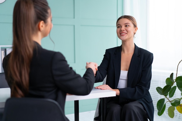 Job interview Business career and placement concept Young blonde woman handshaking candidate hand while sitting in front of candidate during corporate meeting or job interview