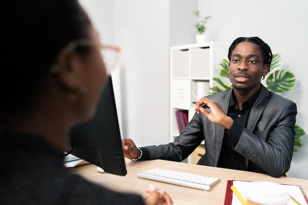 A job interview handsome stern demanding boss sits behind a desk in front of a computer