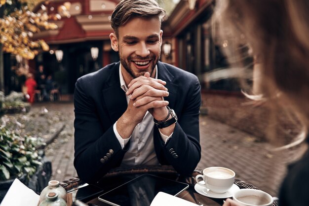 Job interview. Handsome young man in smart casual wear smiling while having a conversation with young woman in restaurant