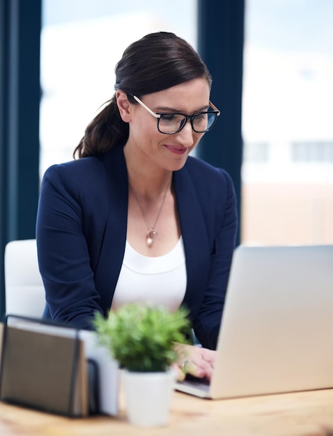 La soddisfazione sul lavoro è un grande motivatore inquadratura di una donna d'affari impegnata che lavora al suo laptop nel suo ufficio