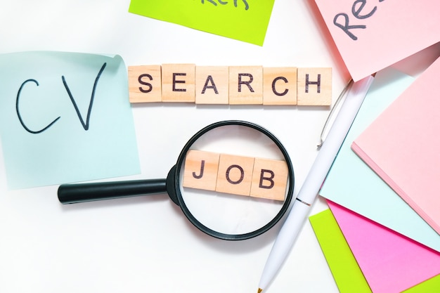 Photo job search concept. job search lettering on the table, many lettering sheets, magnifying glass, drawing up curriculum vitae