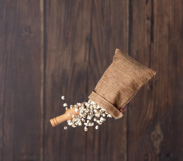 Foto lavori di lacrime che volano in sacchi di grano bianco lavori di lacrime che galleggiano volare su nuvole astratte lavori belli lavori di lacrime di sacchi di lacrime spruzzare nell'aria disegno di oggetti alimentari sfondamento in legno isolato movimento di congelamento ad alta velocità