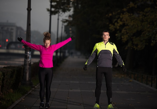 joggend paar opwarmen en strekken voor ochtend hardlopen in de stad