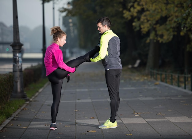 joggend paar opwarmen en strekken voor ochtend hardlopen in de stad