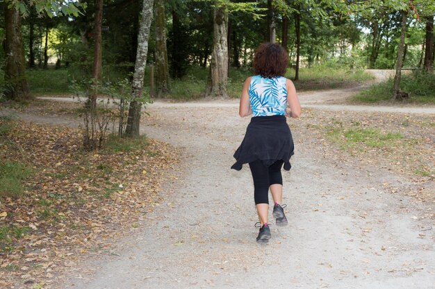 Joggende vrouw die in het park in de zon loopt op een mooie zomer