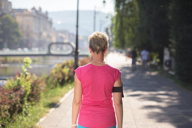 joggende vrouw zet muziek en hardlooproute op smartphone en zet oortelefoons voor ochtendrun