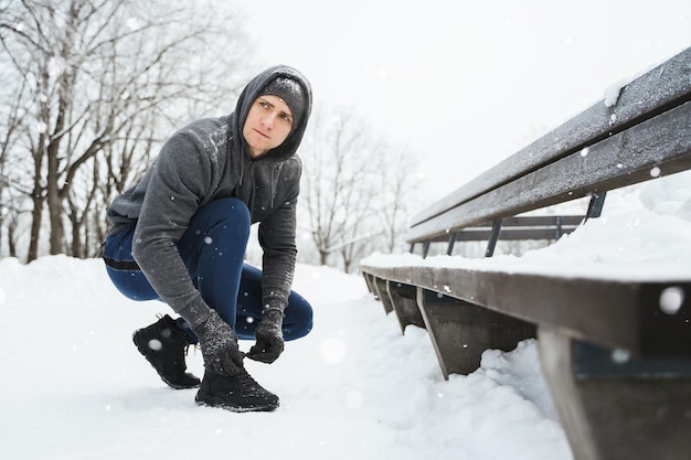 Jogger man is lacing his shoes during his winter workout in a city park