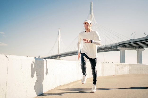 Jogging along the embankment in the city A man running in comfortable sports clothes