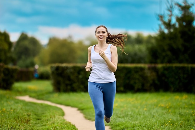 Jogging in city park by happy woman at summer