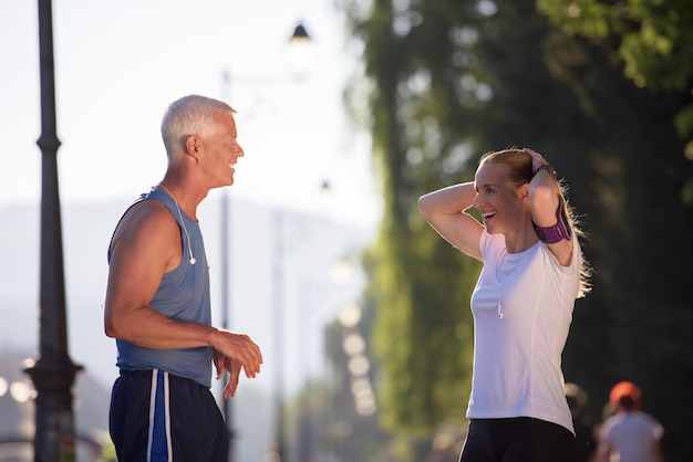 jogging couple check music playlist on phone and plan route before morning running workout  with sunrise in the city  and sun flare in background