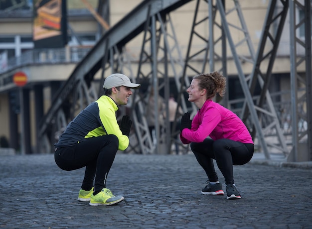 jogging couple warming up and stretching before morning running in the city