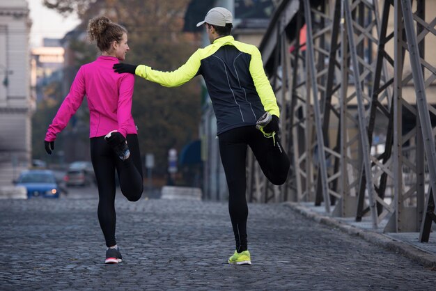 jogging couple warming up and stretching before morning running in the city