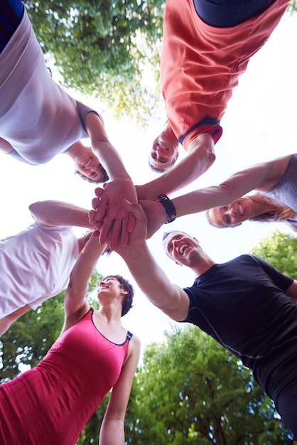 Foto gruppo di persone che fanno jogging, gli amici si divertono, abbracciano e impilano le mani insieme dopo l'allenamento