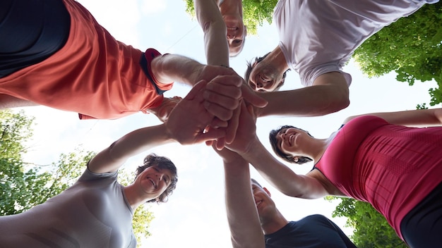 Foto gruppo di persone che fanno jogging, gli amici si divertono, abbracciano e impilano le mani insieme dopo l'allenamento