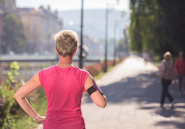 jogging woman setting music and running route on  smart phone putting  earphones before morning run