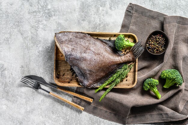 John Dory-vissen op een houten dienblad met rozemarijn en broccoli.