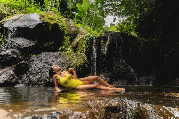 Join me. Cute young woman demonstrating her bright swimsuit while posing on camera, exotic concept