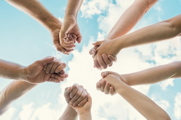 Joined hands as a team Business teamwork Close up group of friends meeting join hands together Diversity people Partnership volunteer community Diverse multiethnic Partners Blue Sky background