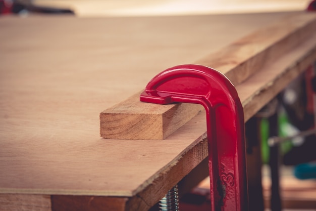 Joiner fastens clamps on a wooden surface for better gluing.