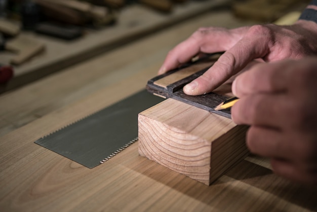 A joiner with a pencil and a square marks the workpiece