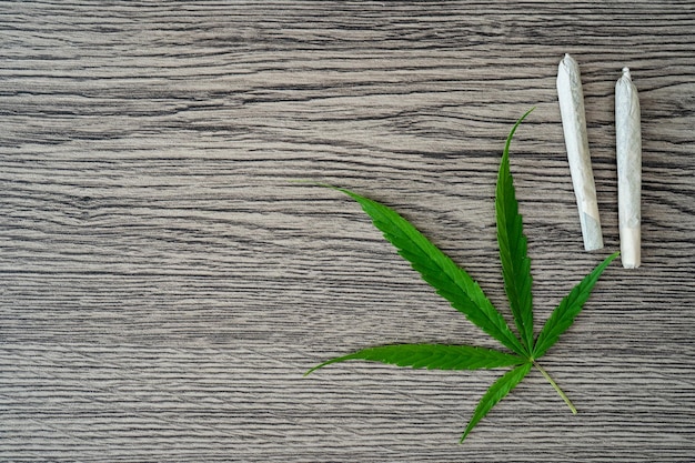 Joints with marijuana leaves on woodden table background