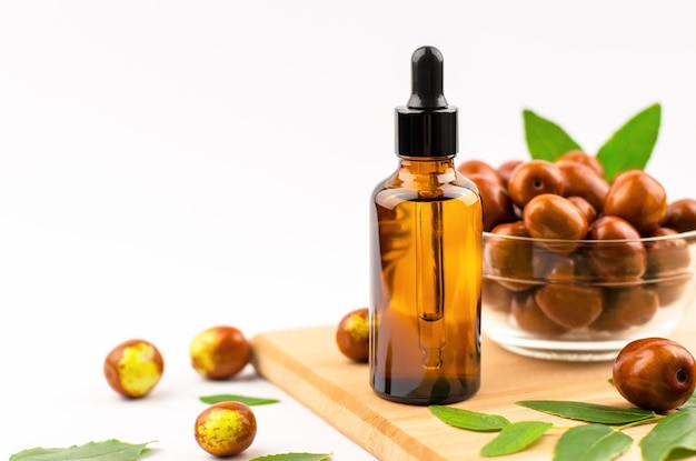 Foto olio di jojoba in una bottiglia con contagocce e frutta fresca di jojoba