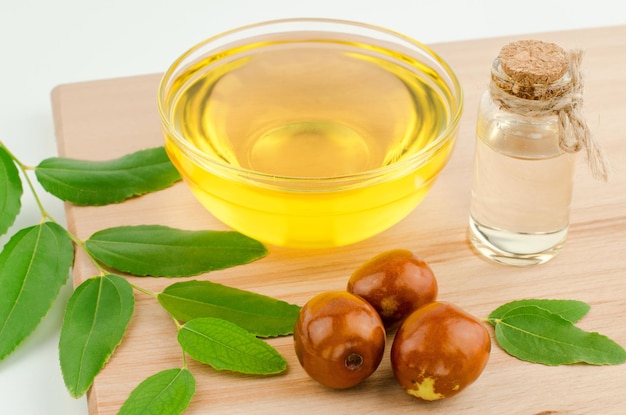 Photo jojoba oil and fresh jujube fruit on wooden background top view