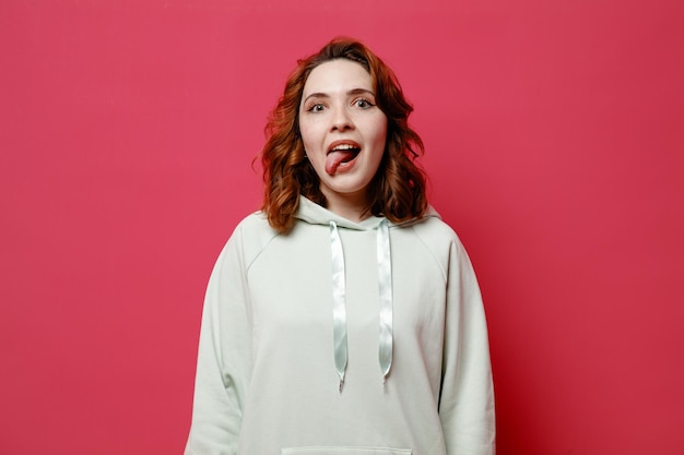 Jokin showing tongue young beautiful girl in white sweater isolated on pink background