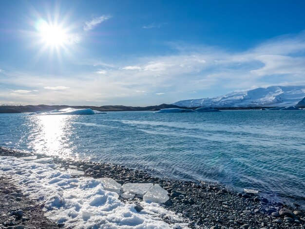 アイスランドの曇った青い空の下に氷河と大きな氷山があるヨークルスアゥルロゥン氷山ラグーン