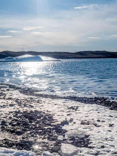 Jokulsarlon iceberg lagoon with glacier and large iceberg under cloudy blue sky in Iceland