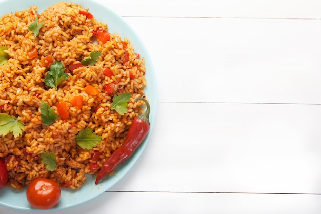 Рисовые помидоры Jollof и острый перец на синей тарелке на белом фоне Национальная кухня Африки Copy spaes