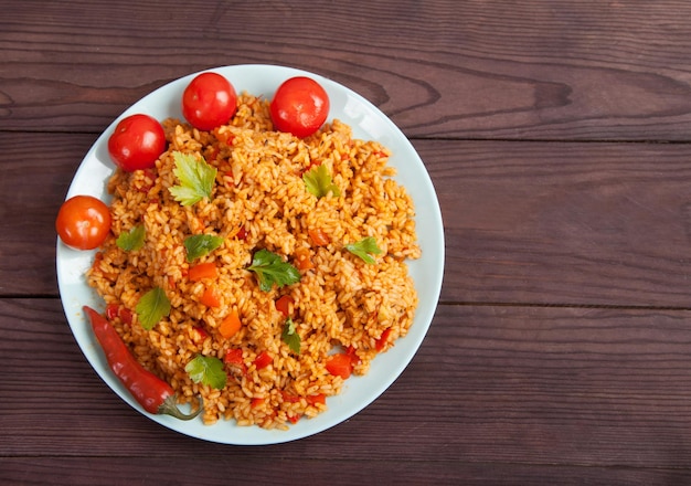 Jollof 쌀, 토마토, 고추 나무 배경에 파란색 접시에. 아프리카의 국가 요리.