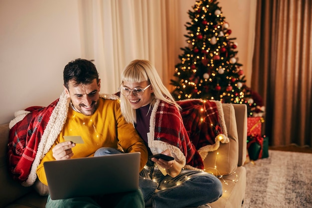 A jolly couple is doing christmas online shopping on christmas and new year at home