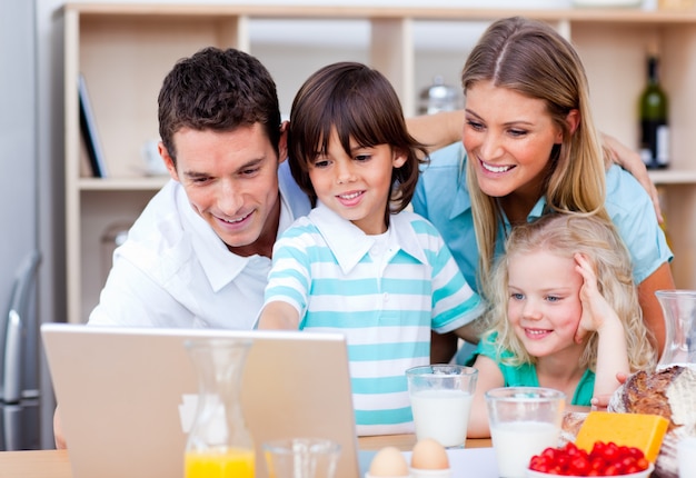 Jolly family using laptop during the breakfast