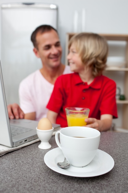 Jolly father and his son having breakfast 