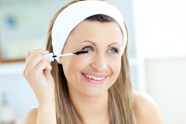 Foto giovane donna allegra che usando mascara nel bagno