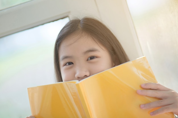 Foto jong aantrekkelijk aziatisch meisje dat thuis een boek leest