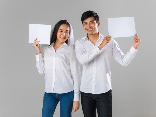 Jong aantrekkelijk aziatisch paar dat een wit overhemd en een sluier draagt die documenten houden