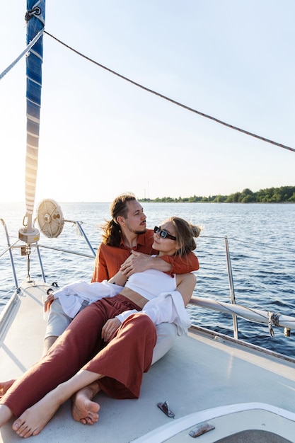 Jong aantrekkelijk echtpaar ontspant zich op de zeilboot tijdens het zeilen op zee