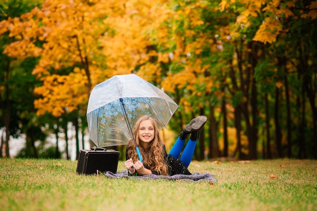 Jong aantrekkelijk glimlachend meisje onder paraplu in de herfstbos