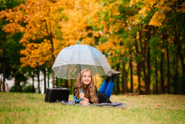 Jong aantrekkelijk glimlachend meisje onder paraplu in een de herfstbos