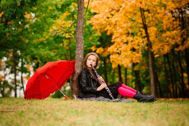 Jong aantrekkelijk glimlachend meisje onder paraplu in een de herfstbos