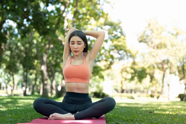 Jong aantrekkelijk meisje doet geavanceerde yoga asana op de fitnessmat in het midden van een park