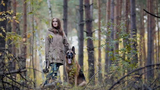 Jong aantrekkelijk meisje en haar huisdier - duitse herder - wandelen in een herfstbos, telefoto